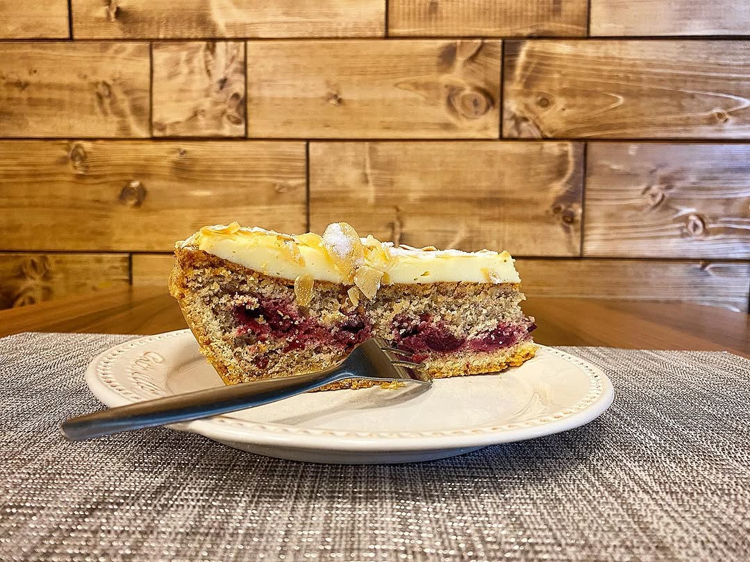 Stück hausgemachter Kirsch-Quark-Kuchen auf weißem Teller, Café Planken Mannheim.